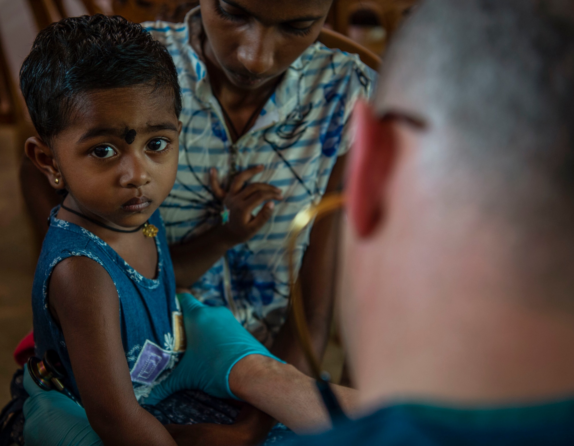 U.S. Air Force Maj. Brad Dayton, 673rd Medical Operations Squadron, Joint Base Elmendorf–Richardson, Alaska, examines a young child during the first day of the Pacific Angel (PAC ANGEL) 18-4 health services outreach event in Vavuniya, Sri Lanka, Aug. 13, 2018.