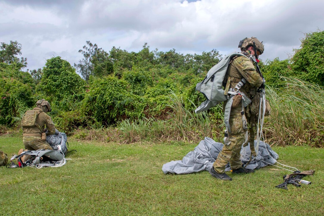 Australian soldiers collect their parachutes and gear.