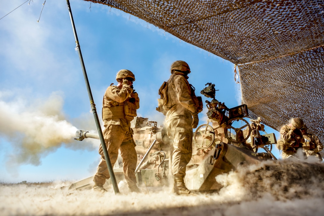 Marines pull the firing mechanism on a Howitzer.