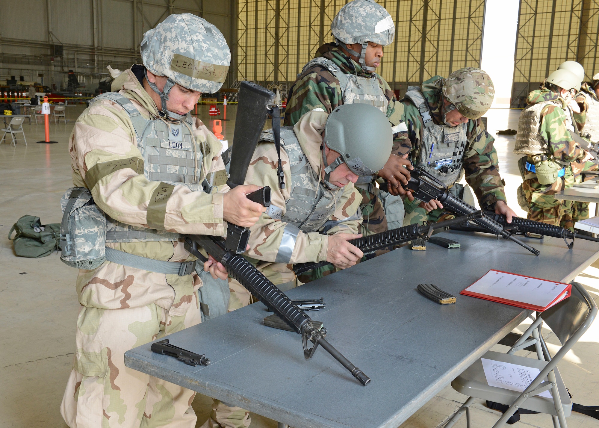 Tech. Sgt. David Leon, 412th Security Forces Squadron (left), disassembles an M-16 assault rifle at one of the exercise stations in Hangar 1600 during Test Wing Readiness Exercise 18-03, Aug. 9. (U.S. Air Force photo by Kenji Thuloweit)