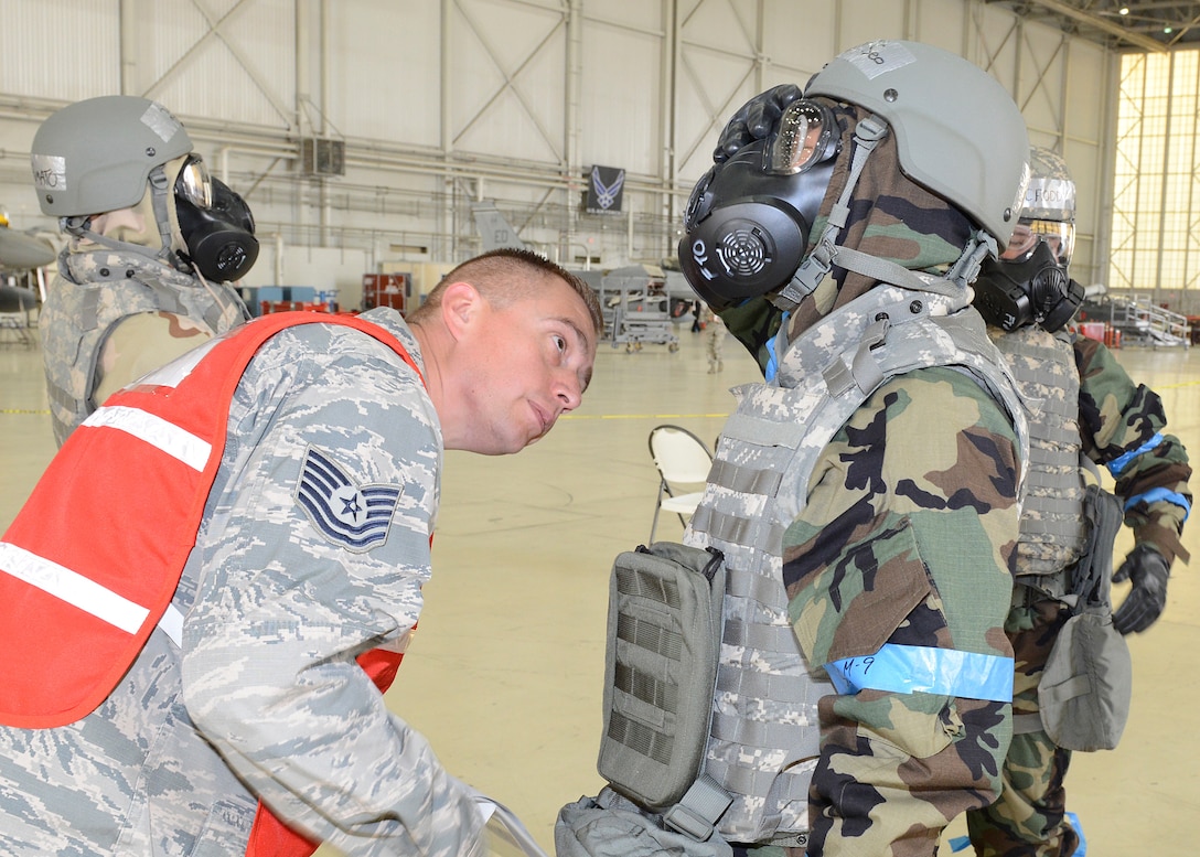 Tech. Sgt. Steven Banda, 412th Maintenance Group, inspects an Airman’s protective mask during Test Wing Readiness Exercise 18-03 held in Hangar 1600, Aug. 9. (U.S. Air Force photo by Kenji Thuloweit)