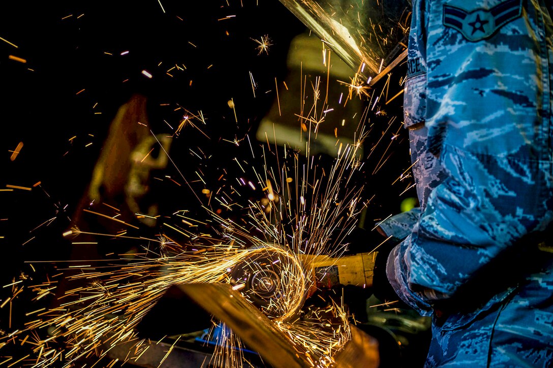 An airman saws through a metal beam.