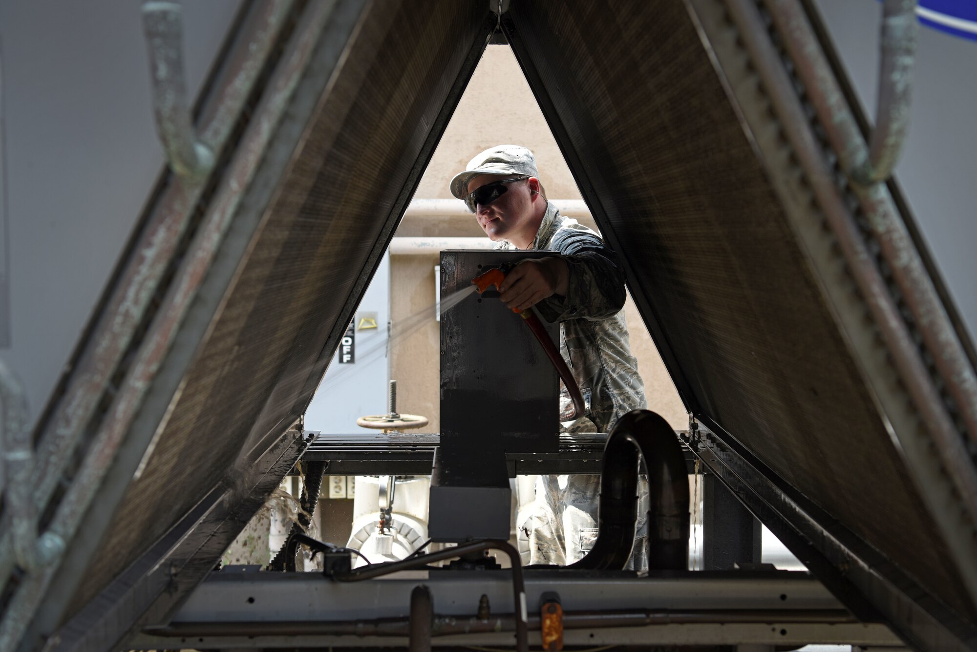 U.S. Air Force Staff Sgt. Matthew Kramer, 51st Civil Engineer Squadron heating, ventilating and air conditioning journeyman, cleans off a cooling unit at the dorms to allow better heat dispersion at Osan Air Base, Republic of Korea, Aug. 13, 2018. Over the summer, the HVAC Airmen completed 175 work orders in 249 dorm rooms in two days. (U.S. Air Force photo by Senior Airman Kelsey Tucker)
