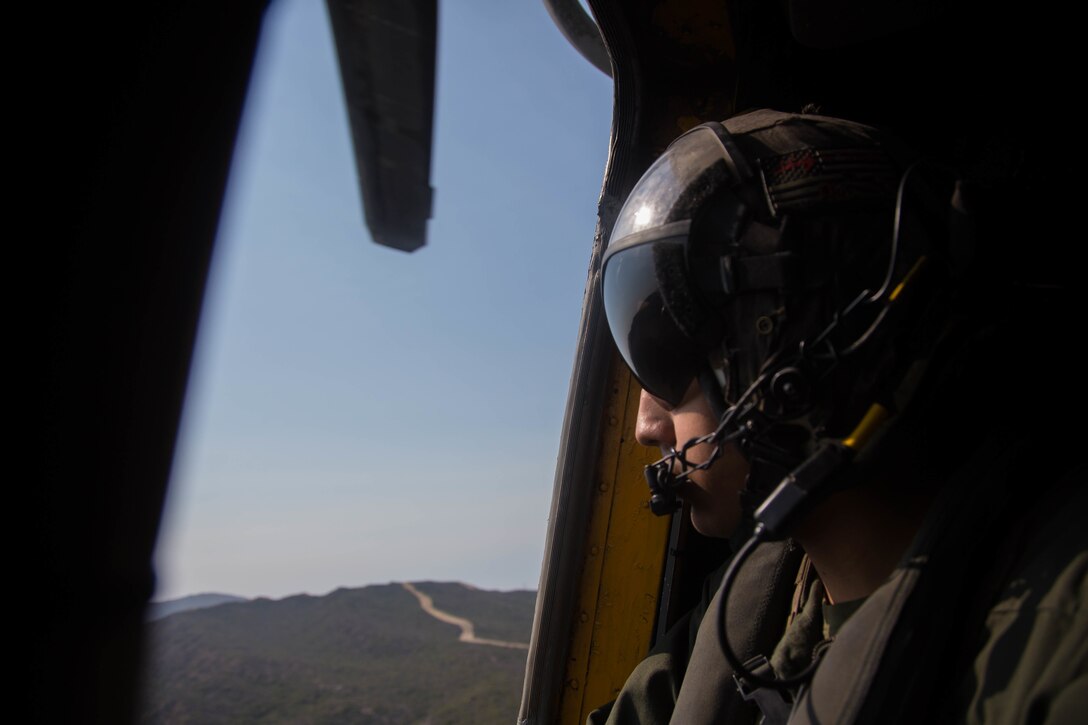 Sgt. Xavier Rodriguez, a crew chief with Marine Heavy Helicopter Squadron 465, Marine Aircraft Group 16, 3rd Marine Aircraft Wing, scans the terrain from a CH-53E Super Stallion helicopter over Marine Corps Base Camp Pendleton, Calif., Aug. 10. During flight, crew chiefs are subject matter experts on aircraft operations and terrain features. HMH-465 conducts training with Amphibious Raids Branch, Expeditionary Operations Training Group, I Marine Expeditionary Force, to assist infantry Marines performing fast-rope training from a helicopter.