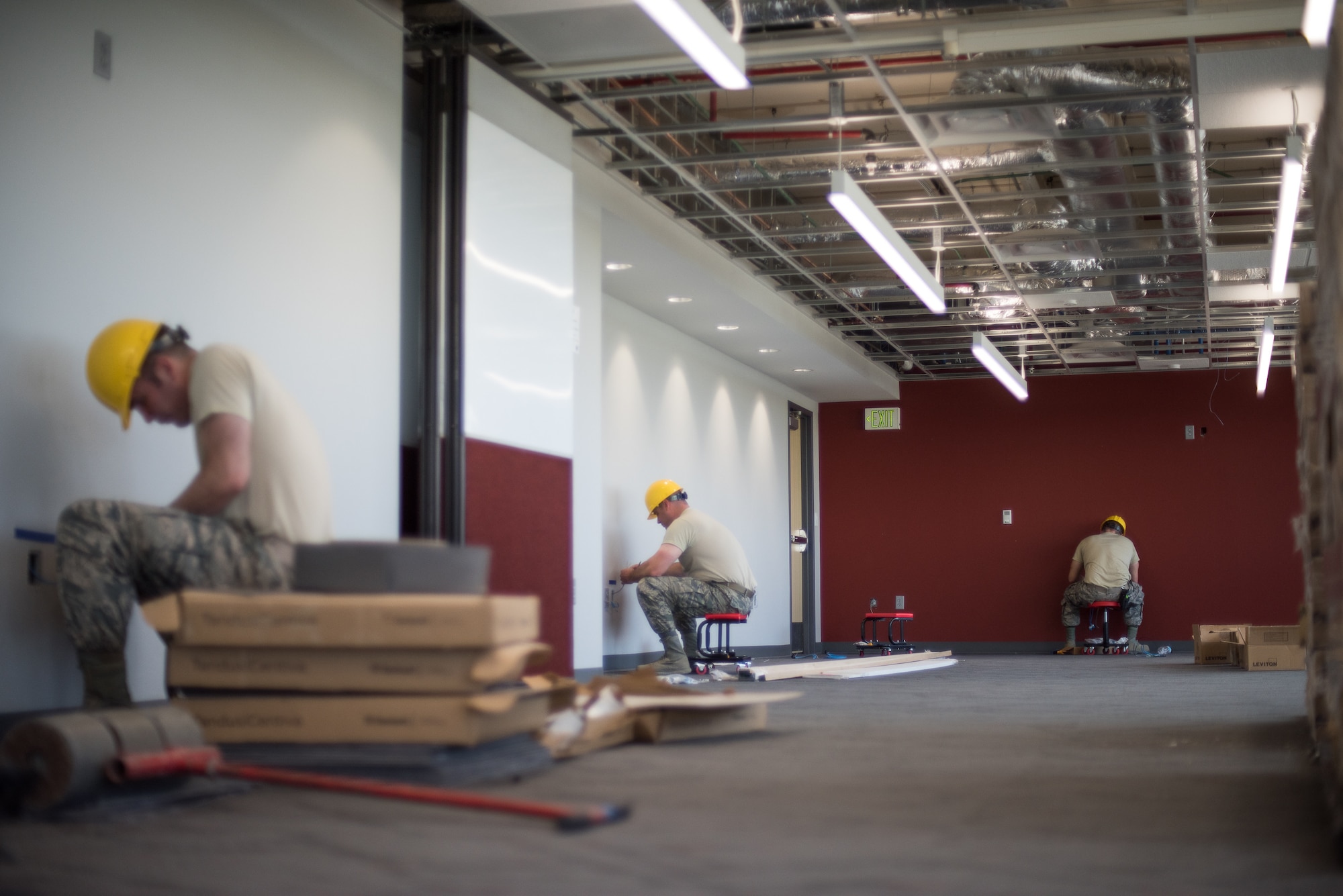 Three Airmen from the 205th Engineering and Installation Squadron (205th EIS) terminate cables that have been dropped down the wall into ports that will be used by the end user for telephone and internet service during a hangar renovation project at Buckley Air Force Base in Aurora, Colorado, July 20, 2018. The 205th EIS team, from Will Rogers Air National Guard Base in Oklahoma City, completed more than 1,000 cable drops and installed an estimated 200,000 feet of indoor cable as part of the 6-week install for the renovation, which was estimated to be $22 million project in total. (U.S. Air National Guard photo by Staff Sgt. Kasey M. Phipps)