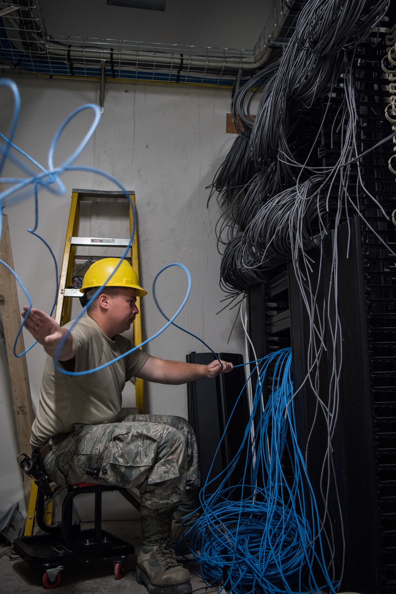 Staff Sgt. Tyler Evans, a 205th Engineering and Installation Squadron (205th EIS) cable installations Airman, feeds cable as he creates a telecommunications connection point in the main distribution frame, where communications from outside the building are routed and connected to internal networks, July 24, 2018, during a hangar renovation project at Buckley Air Force Base in Aurora, Colorado. The 205th EIS team, from Will Rogers Air National Guard Base in Oklahoma City, completed more than 1,000 cable drops and installed an estimated 200,000 feet of indoor cable as part of the 6-week install for the renovation, which was estimated to be a $22 million project in total. (U.S. Air National Guard photo by Staff Sgt. Brigette Waltermire)