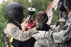 Two soldiers hold onto a child in a helicopter after rescuing him from floodwaters in Pennsylvania.