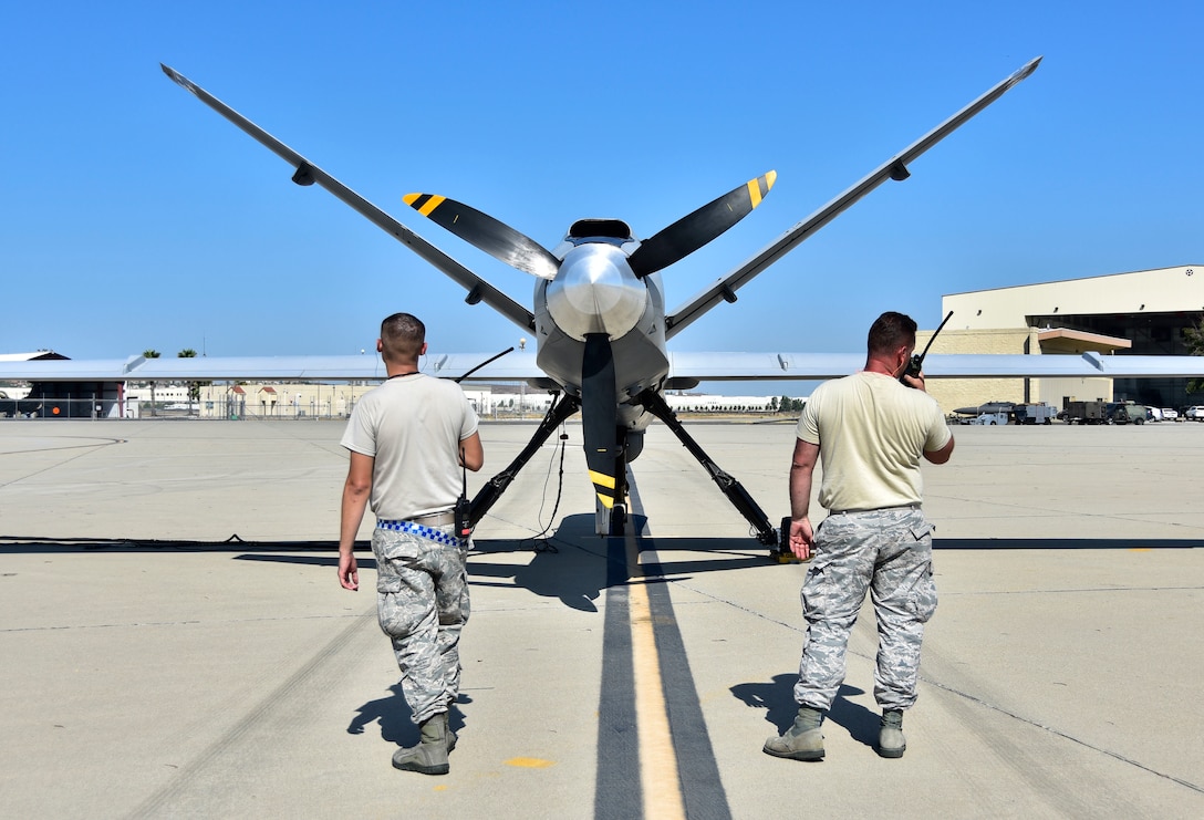 Airmen do a preflight check on a drone.