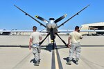 Airmen do a preflight check on a drone.