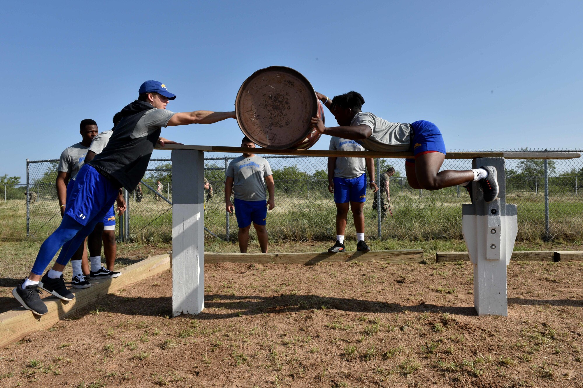 Angelo State University students, Payne Sullins and Bam Howard, move a barrel over the Benavidez’s Rescue obstacle on Goodfellow Air Force Base, Texas, Aug, 15, 2018. Each course has three parts, delivering supplies or wounded personnel over difficult terrain and ensuring the safe passage of each team member. (U.S. Air Force photo by Senior Airman Randall Moose/Released)