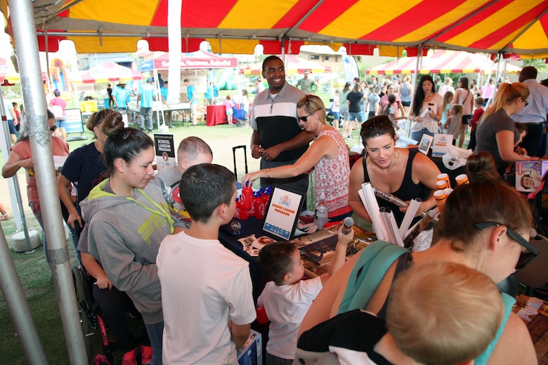 Family members swarm booths during the Back to School Bash at Victory Field, Marine Corps Air Ground Combat Center, Twentynine Palms, Calif., Aug. 10, 2018. About 1,500 attended the event sponsored by Marine Corps Community Service and the Combat Center School Liaison. (Marine Corps photos by Kelly O'Sullivan)