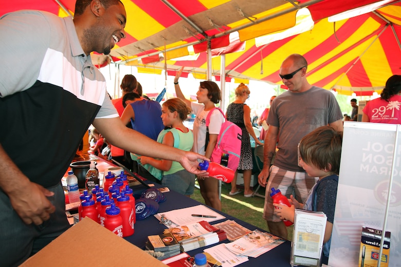 Walter Parham, School Liaison, hands out water bottles to family members during the Back to School Bash at Victory Field, Marine Corps Air Ground Combat Center, Twentynine Palms, Calif., Aug. 10, 2018. About 1,500 attended the event hosted by Marine Corps Community Services and the Combat Center School Liaison. (Marine Corps photo by Kelly O'Sullivan)