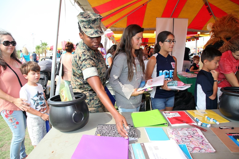 Staff Sgt. Rose Reed, Headquarters Company, Marine Corps Communication-Electronics School, Marine Corps Air Ground Combat Center, Twentynine Palms, Calif., picks up school supplies during the Back to School Bash at Victory Field, Aug. 10, 2018. About 1,500 attended the event hosted by Marine Corps Community Services and the Combat Center School Liaison. (Marine Corps photo by Kelly O'Sullivan)