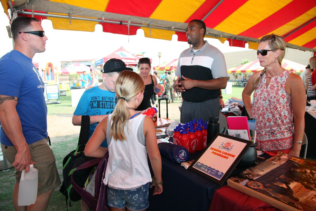 Walter Parham, School Liaison, center, and Kim Pope, Community Liaison, talk with family members during the Back to School Bash at Victory Field, Marine Corps Air Ground Combat Center, Twentynine Palms, Calif., Aug. 10, 2018. About 1,500 attended the event hosted by Marine Corps Community Services and the Combat Center School Liaison. (Marine Corps photo by Kelly O'Sullivan)