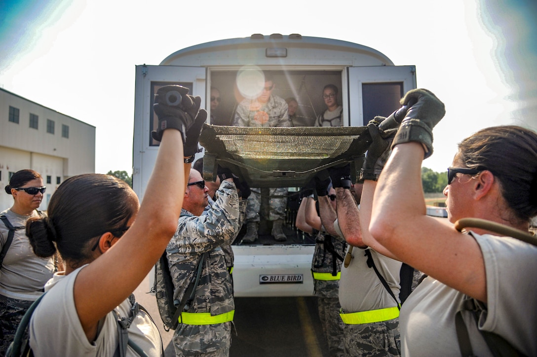 Airmen lift a litter onto a bus.