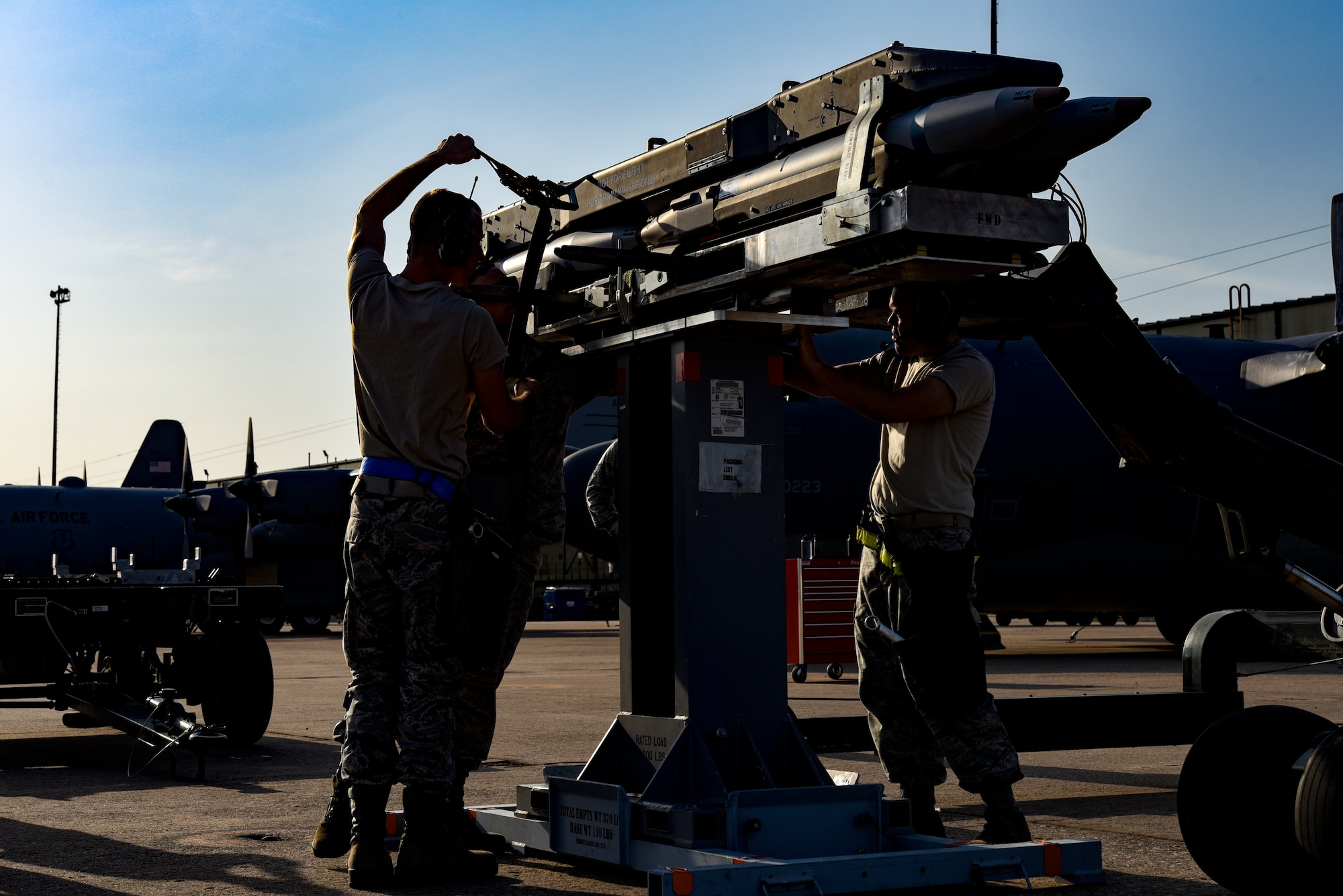 Airmen strap in bombs to the bomb cradle. They use belts and bolted straps.