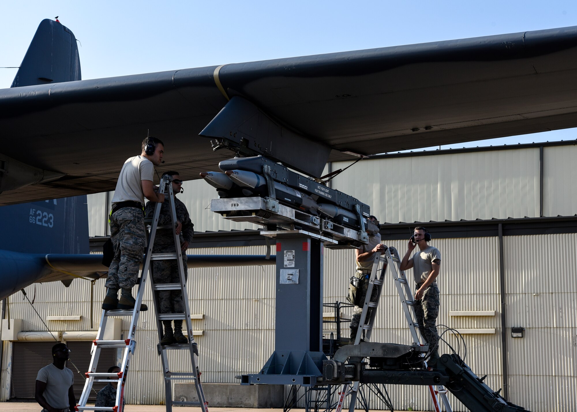 Airmen stand on ladders to make sure the loading bombs are aligned correctly.