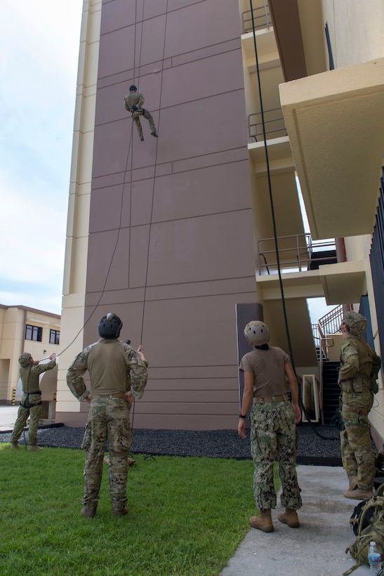 U.S. sailors and Australian soldiers repel from a tower during unit-level training.