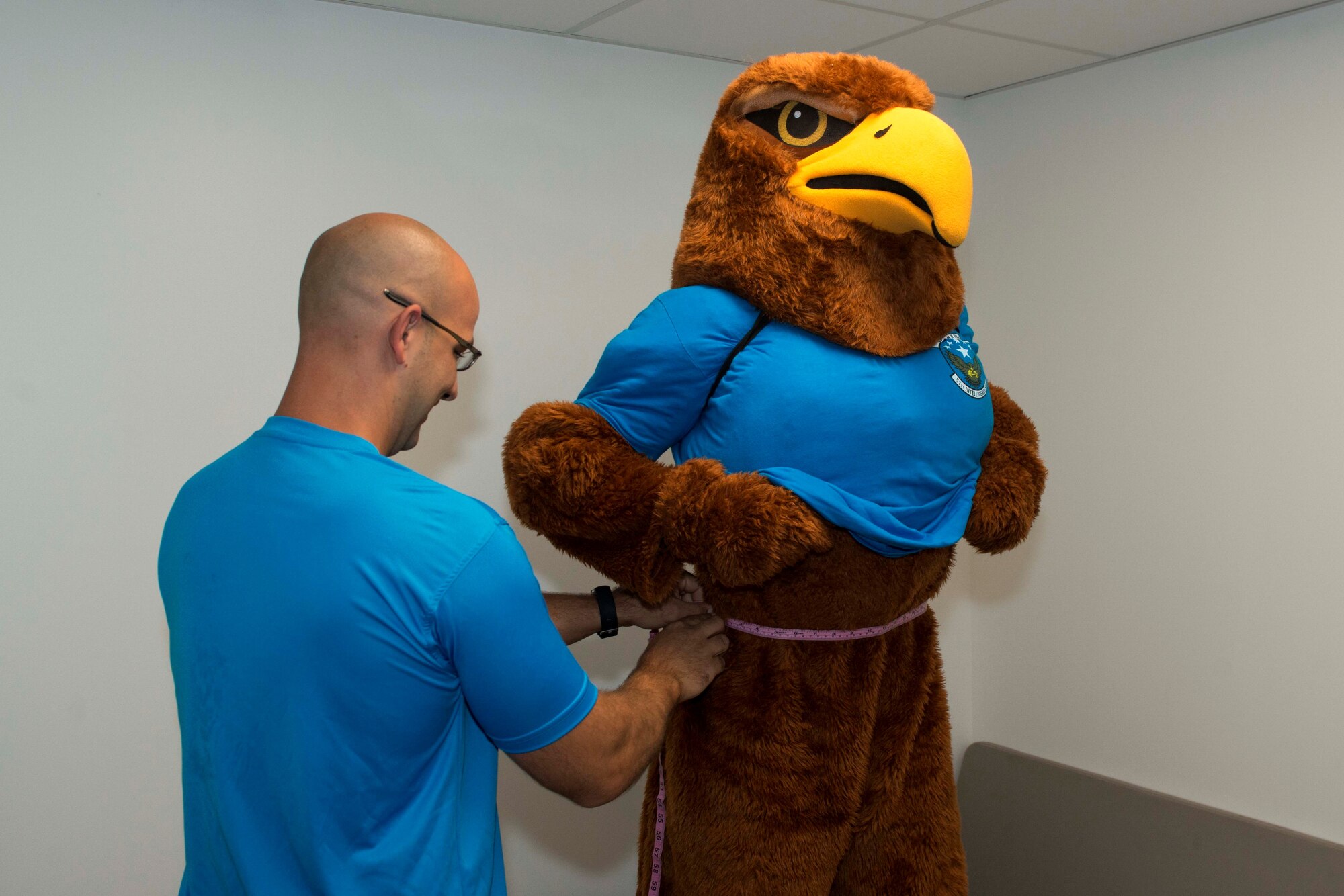 U.S. Air Force Airman Tanner Smith, 51st Intelligence Squadron (IS) intelligence analyst, demonstrates proper waist measurement procedure wearing the 51st IS mascot costume at Shaw Air Force Base, S.C., Aug. 15, 2018.