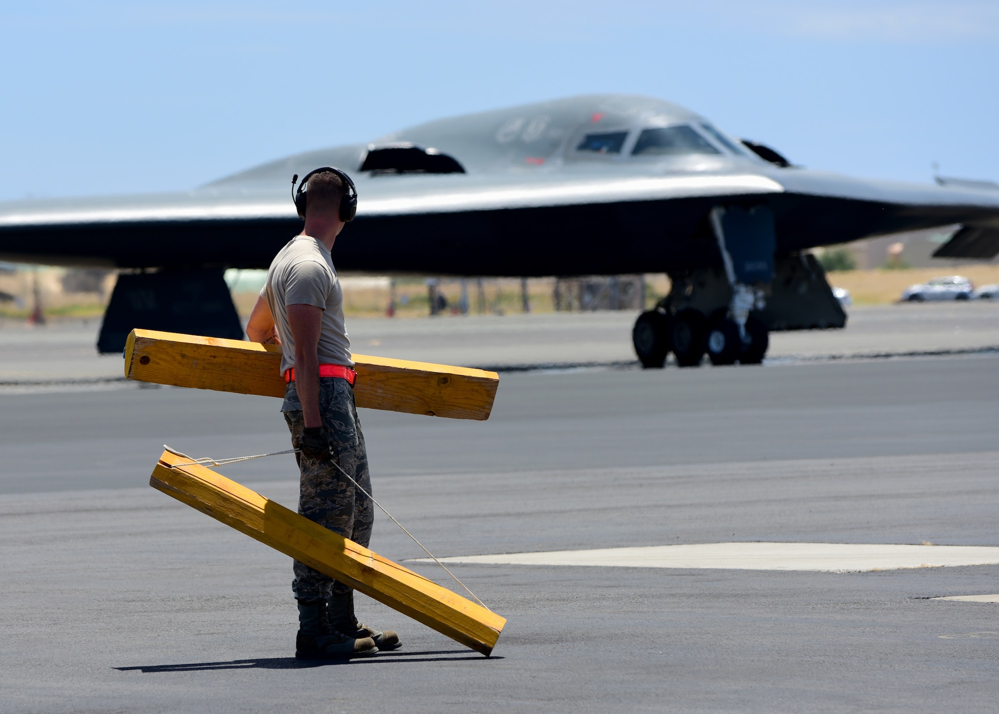 A U.S. Air Force maintenance technician from Whiteman Air Force Base, Missouri, prepares to place wheel chocks on a B-2 Spirit at Joint Base Pearl Harbor-Hickam, Hawaii, Aug. 15, 2018. B-2s regularly rotate through the Indo-Pacific to conduct routine air operations, which integrate capabilities with key regional partners and demonstrate U.S. commitment to peace and stability in the region. These operations are in support of the U.S. Strategic Command’s Bomber Task Force deployment. (U.S. Air Force photo by Staff Sgt. Danielle Quilla)