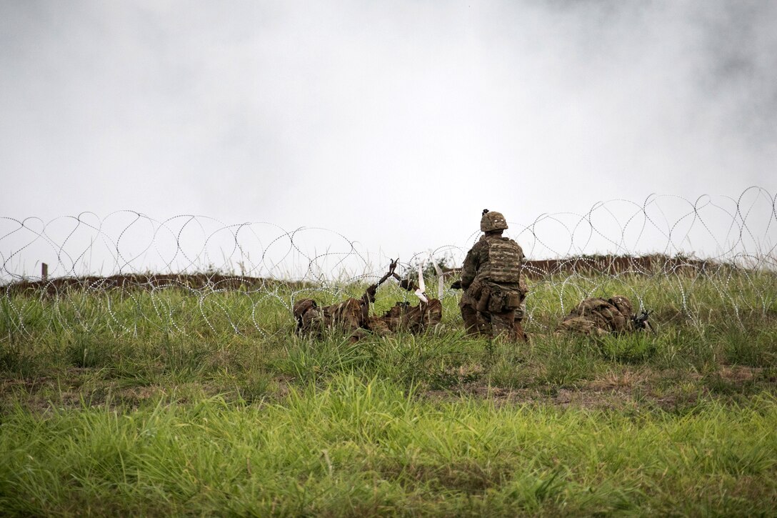 Soldiers breach a concertina wire obstacle.