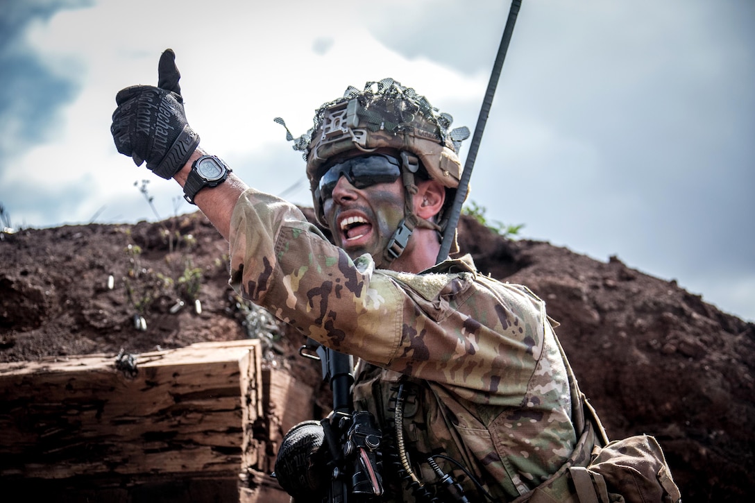 A soldier signals to his squad during a combined arms live-fire exercise.