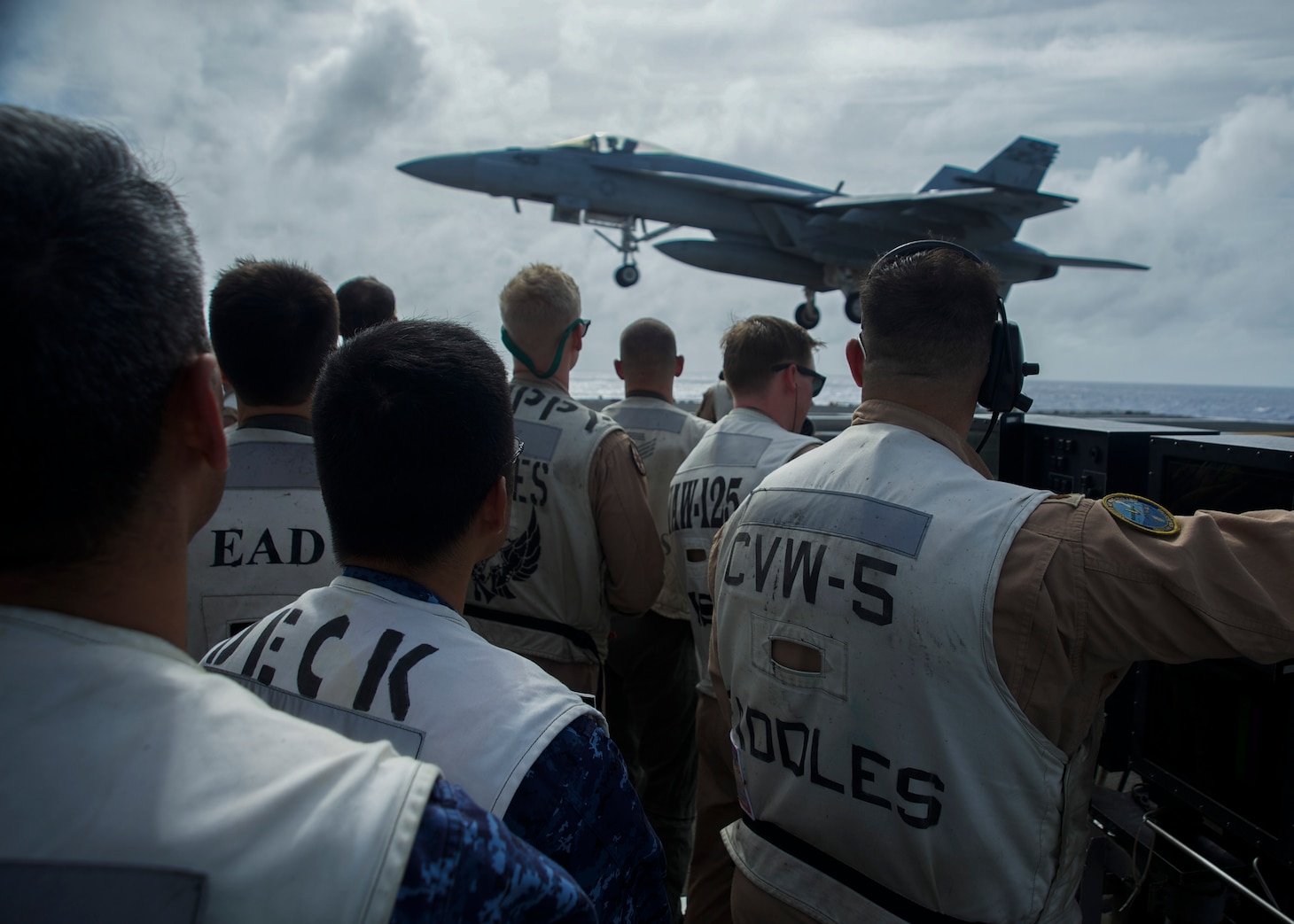 PHILIPPINE SEA (Aug. 15, 2018) JMSDF officers and U.S. Navy officers watch an F/A-18E Super Hornet, assigned to the “Dambusters” of Strike Fighter Squadron (VFA) 195, land on the aircraft carrier USS Ronald Reagan (CVN 76) during flight operations. Ronald Reagan is forward-deployed to the U.S. 7th Fleet area of operations in support of security and stability in the Indo-Pacific region.