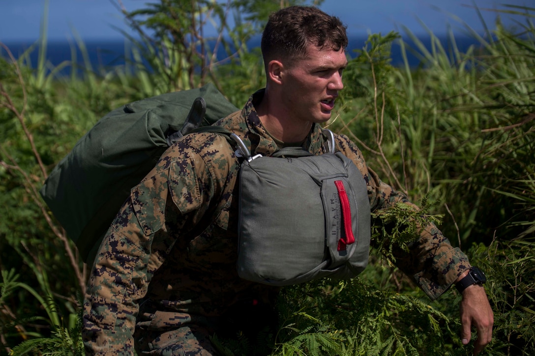 Cpl. Dustin Murphy climbs out of the brush after jumping out of a CH-53E Super Stallion during parachute training operations Aug. 13, 2018 at Ie Shima, Okinawa, Japan. Landing Support Company completed parachute and air delivery training to ensure Marines maintain proficiency and meet required training hours. Murphy, a parachute rigger with Air Delivery Platoon, LS Co., 3rd Transportation Support Battalion, is a native of Indianapolis, Indiana. (U.S. Marine Corps photo by Lance Cpl. Jamin M. Powell)