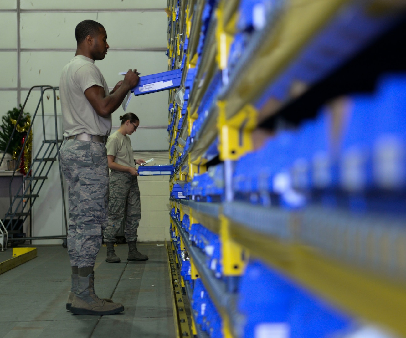 U.S Air Force Airman 1st Class Jimmy Ogletree, 100th Logistics Readiness Squadron aircraft parts store journeyman, front, and Staff Sgt. Morgan Petter, 100th LRS APS supervisor find aircraft parts for an order request at RAF Mildenhall, England, Aug. 8, 2018. The APS supplies the aircraft with mobility readiness spare part kits. Each package is tailored to support an aircraft for the first 30 days of a deployment. (U.S. Air Force photo by Airman 1st Class Alexandria Lee)