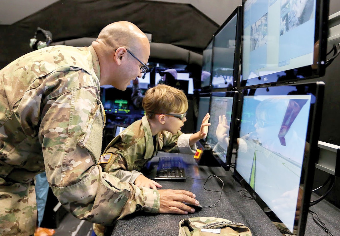 Army Chief Warrant Officer 3 Saul Mulholland, 3rd Assault Helicopter Battalion, 4th Aviation Regiment, shows Carson Raulerson how flight instructors can control environmental variables for pilots training on the Black Hawk simulator at Fort Carson, Colo. Army photo by Sgt. Anthony Bryant