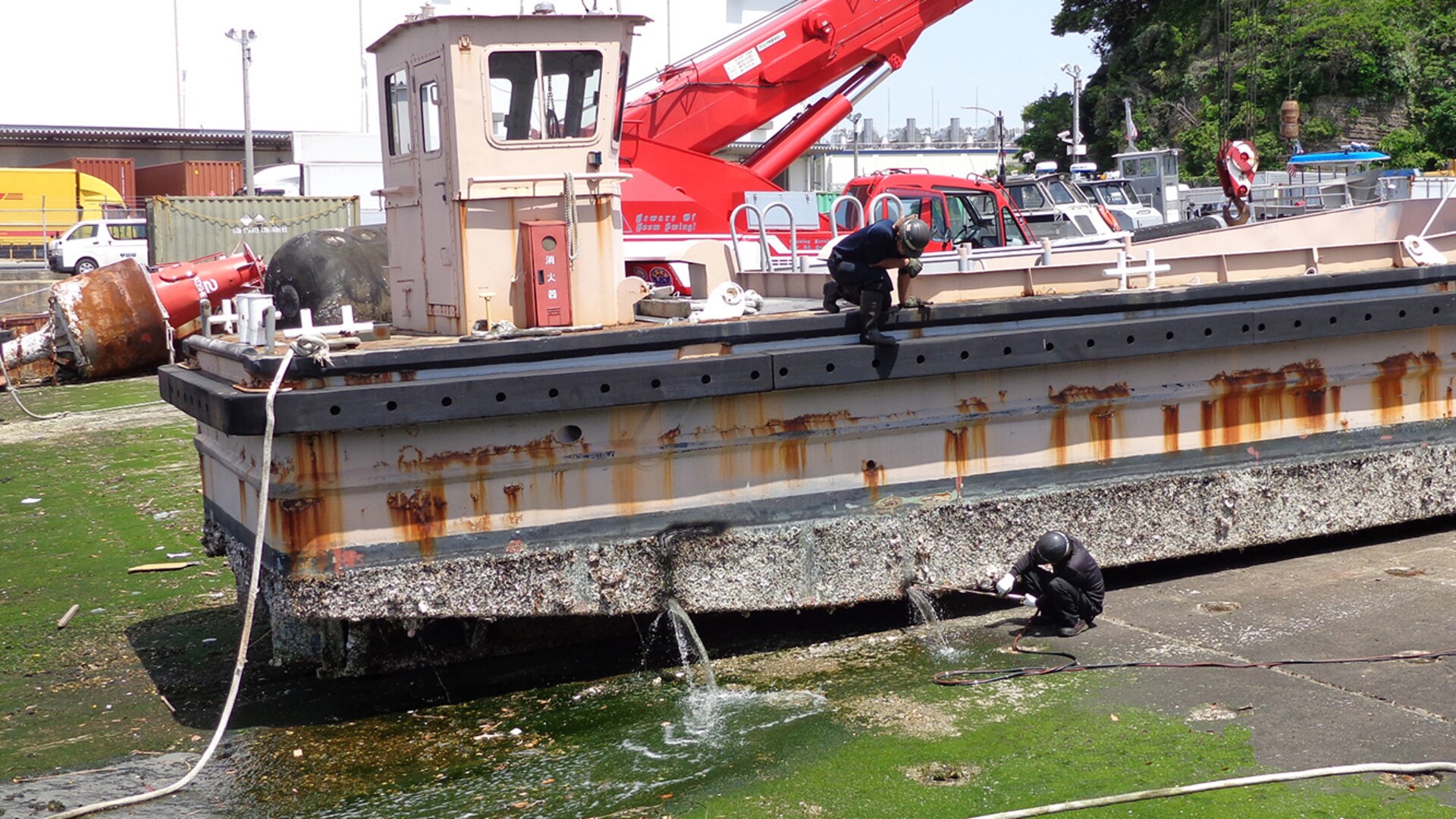 A scrap contractor employee uses a torch to cut pieces of a large work boat even smaller.