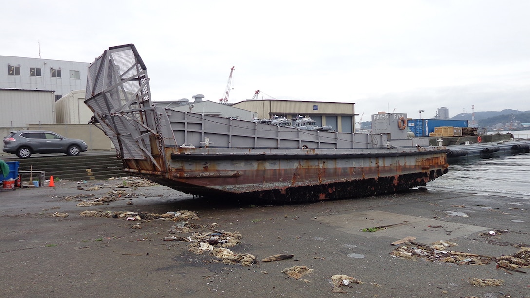 Scrap contractor employees begin the mutilation required to demilitarize a 56-foot naval work boat.