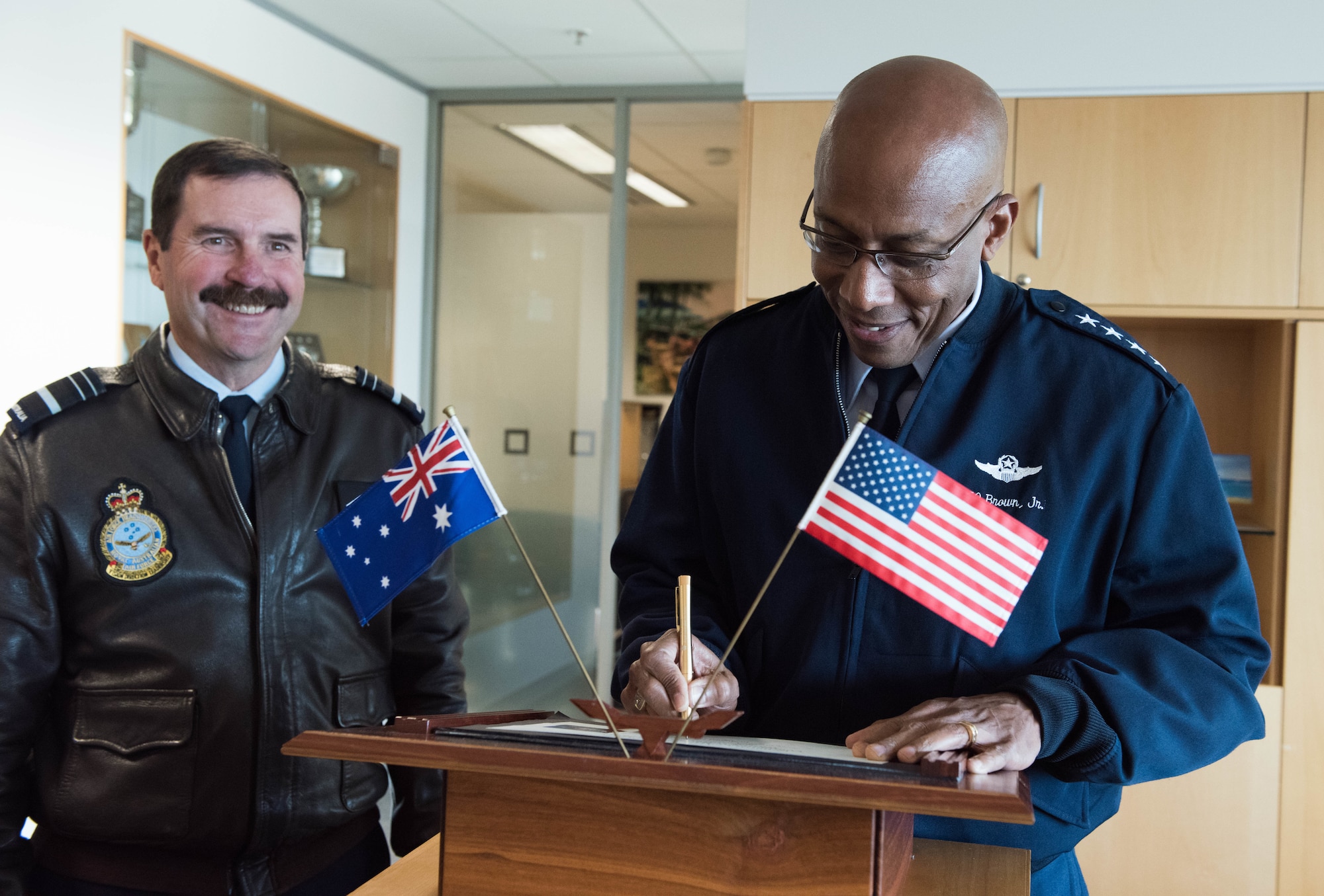 Gen. CQ Brown, Jr., Pacific Air Forces commander, signs a guest book before an office call with Air Marshal Leo Davies (left), Royal Australian Air Force (RAAF) chief of Air Force, at the Russell offices, Canberra, Australia, Aug. 10, 2018. His first trip to the region since taking command on July 26, 2018, Brown met with key defense and military leaders in Canberra and RAAF Bases Williamtown, Tindal and Darwin to see first-hand the strength of the U.S.-Australia alliance and discuss opportunities to ensure a free and open Indo-Pacific region. (U.S. Air Force photo by Staff Sgt. Hailey Haux)