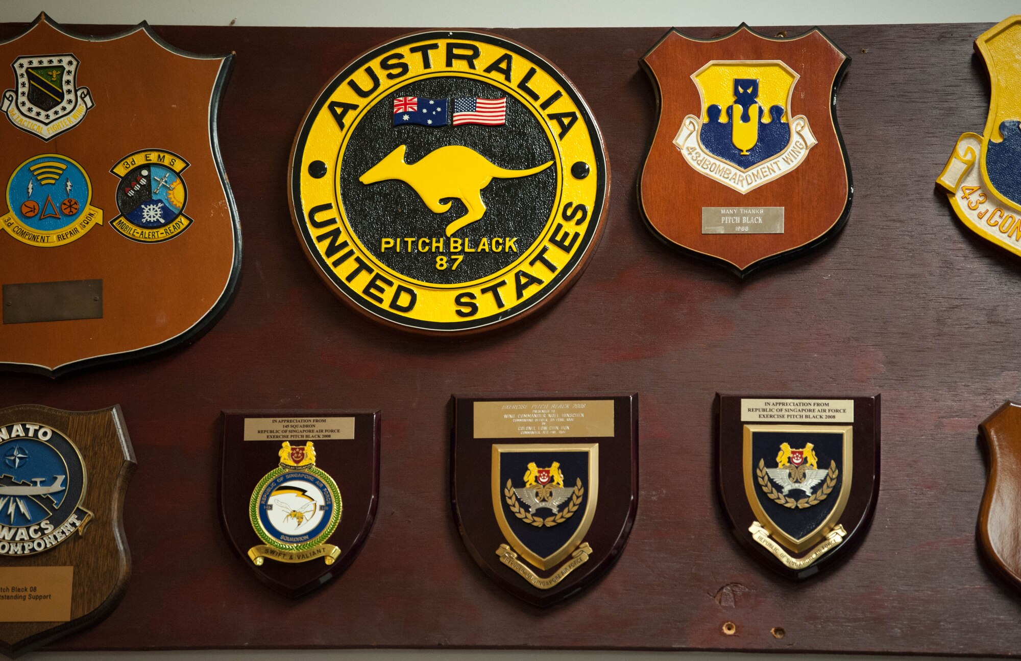 A plaque showcasing U.S. participation in a previous iteration of Exercise Pitch Black hangs at the exercise headquarters among many other plaques from various nations at Royal Australian Air Force Base Darwin, Australia, Aug. 13, 2018. This year’s biennial multinational large force employment exercise is the largest since its inception, involves 16 nations, 140 aircraft and more than 4,000 personnel.  (U.S. Air Force photo by Staff Sgt. Hailey Haux)