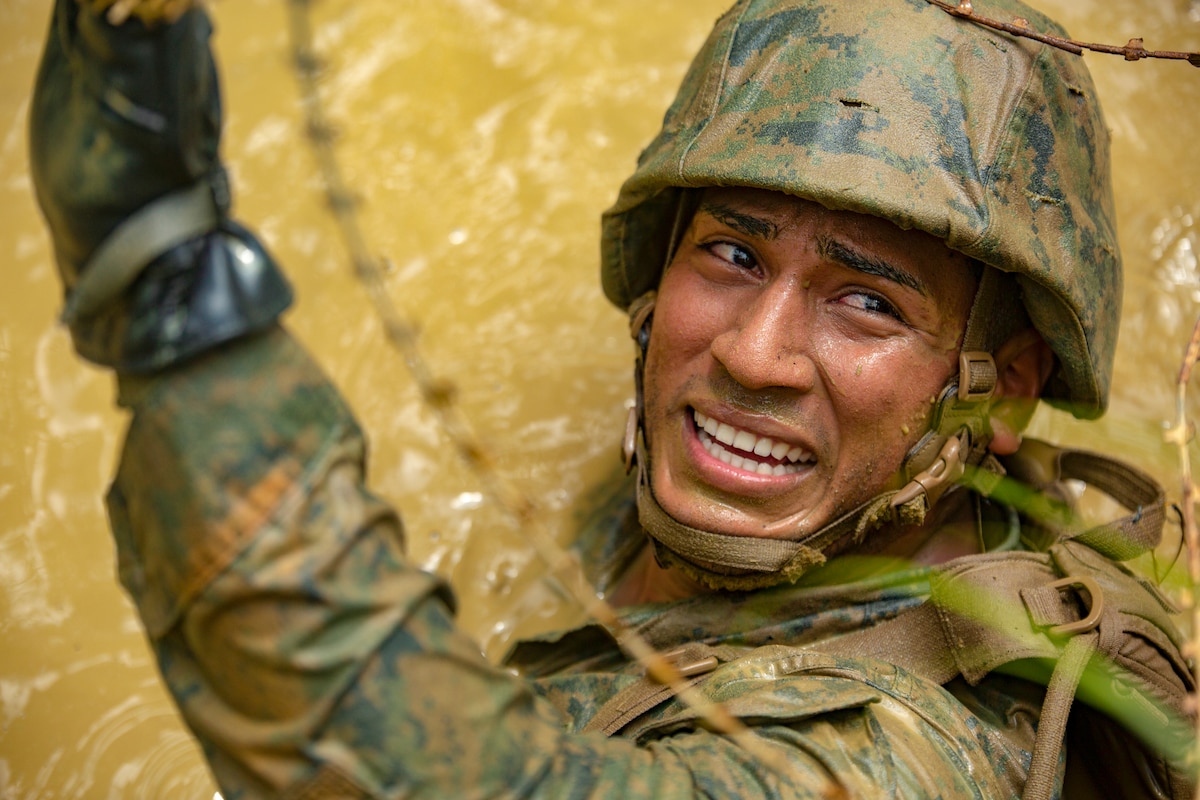 A sailor maneuvers through murky water, confined spaces and razor wire.