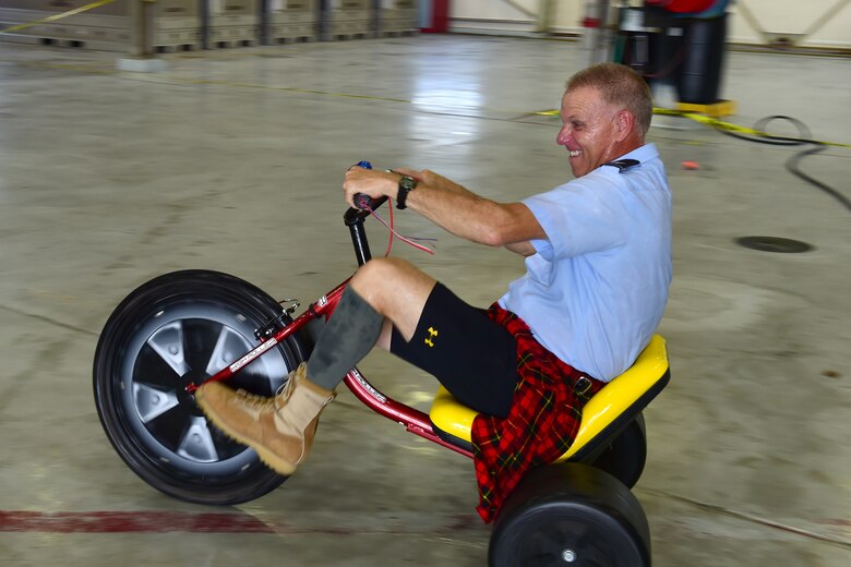 Col. Larry Shaw, 434th Air Refueling Wing commander, races a tricycle around a maintenance dock during a combat dining in at Grissom Air Reserve Base, Ind., Aug. 18, 2018. Grissom held its first combat dining in since 2007, where Airmen faced several fun challenges and were encouraged to show off their homemade uniforms. (U.S. Air Force Photo / Staff Sgt. Christopher Massey)