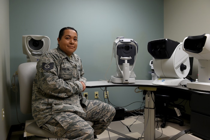 Photo of Staff Sgt. Ivonn Denton sitting in front of eye exam machines.