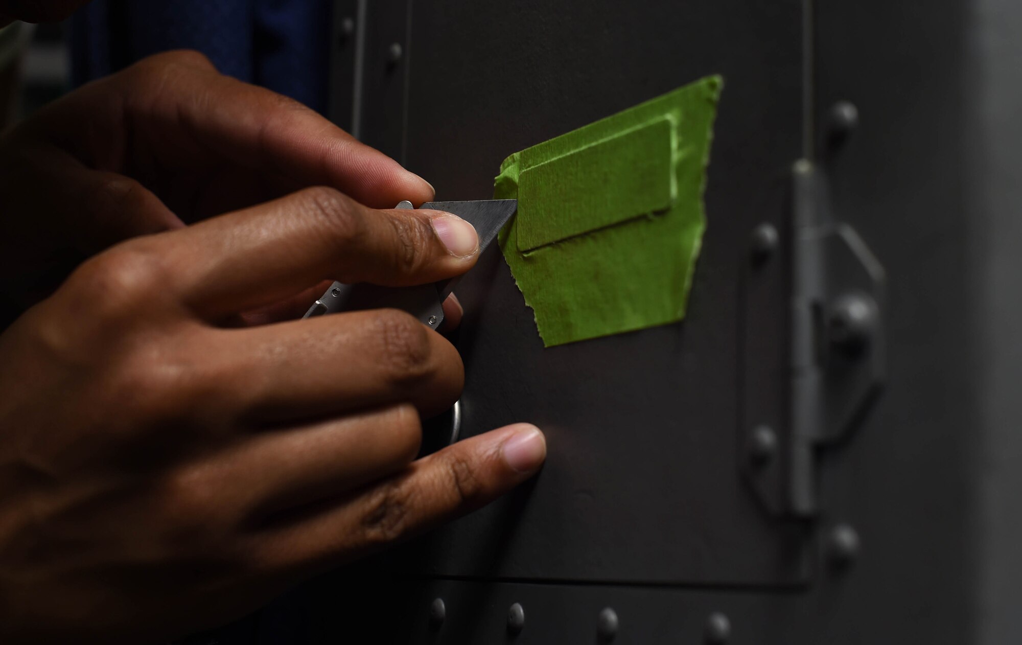 Airman 1st Class Ariel Smith, 60th Maintenance Squadron aircraft structural maintenance technician, cuts away unnecessary tape while preparing to paint inside a C-17 Globemaster III from Travis Air Force Base, Calif., Aug. 6, 2018, at Joint Base Lewis-McChord, Wash. Smith and other Travis Airmen painted the metal components inside and outside the aircraft as a part of corrosion prevention. (U.S. Air Force photo by Senior Airman Tryphena Mayhugh)