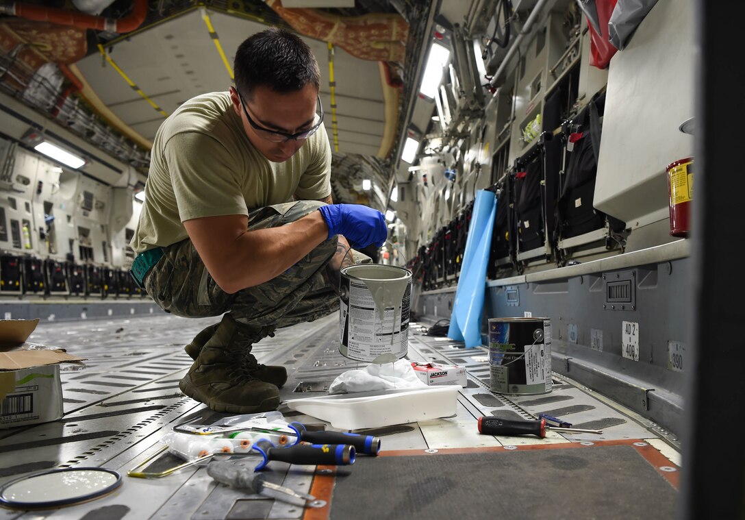 Staff Sgt. Fernando Ortiz, 60th Maintenance Squadron aircraft structure maintenance technician, pours paint into a container inside a C-17 Globemaster III from Travis Air Force Base, Calif., Aug. 6, 2018, at Joint Base Lewis-McChord, Wash. Ortiz and other Travis Airmen painted the metal components inside and outside the aircraft as a part of corrosion prevention. (U.S. Air Force photo by Senior Airman Tryphena Mayhugh)