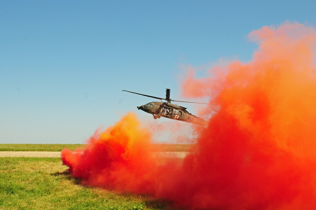 A helicopter takes off surrounded by red smoke.