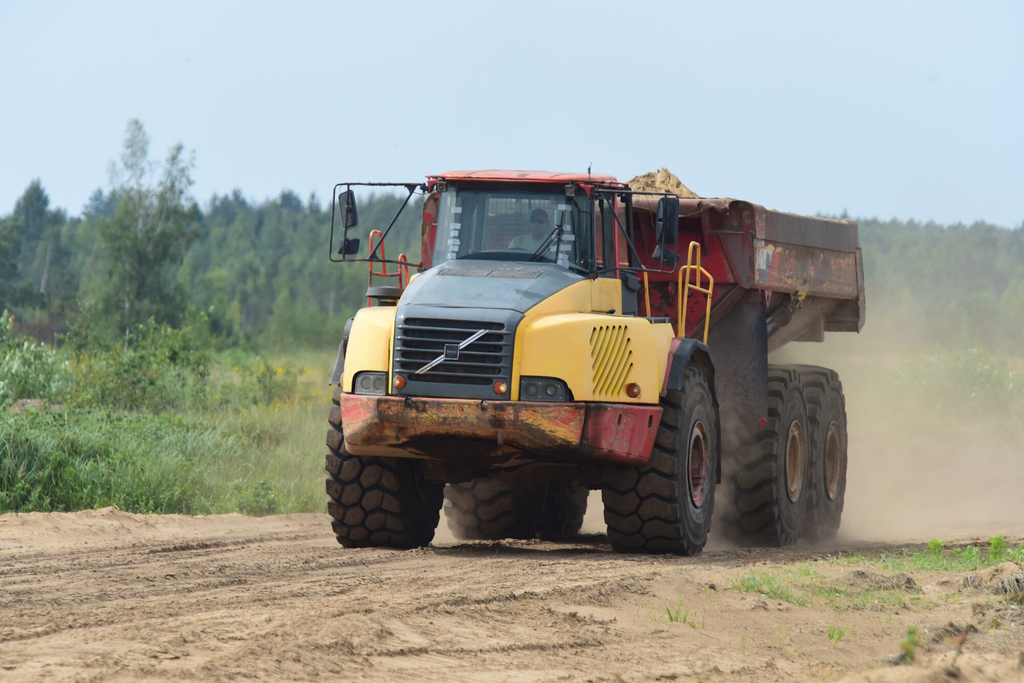 A dump truck operated by an Airman from the 201st Rapid Engineer Deployable Heavy Operational Repair Squadron Engineers, hauls in fill to an area of the training air-to-ground range being constructed at Brigadier General Kazio Veverskis Training Grounds, Kazlu Ruda, Lithuania, Aug. 14, 2018. The range will include a mock village, bomb circle, simulated runway, fire break, strafe pit and observation point to be used by Lithuanian and other NATO forces. (U.S. Air National Guard photo by Tech. Sgt. Claire Behney/Released)