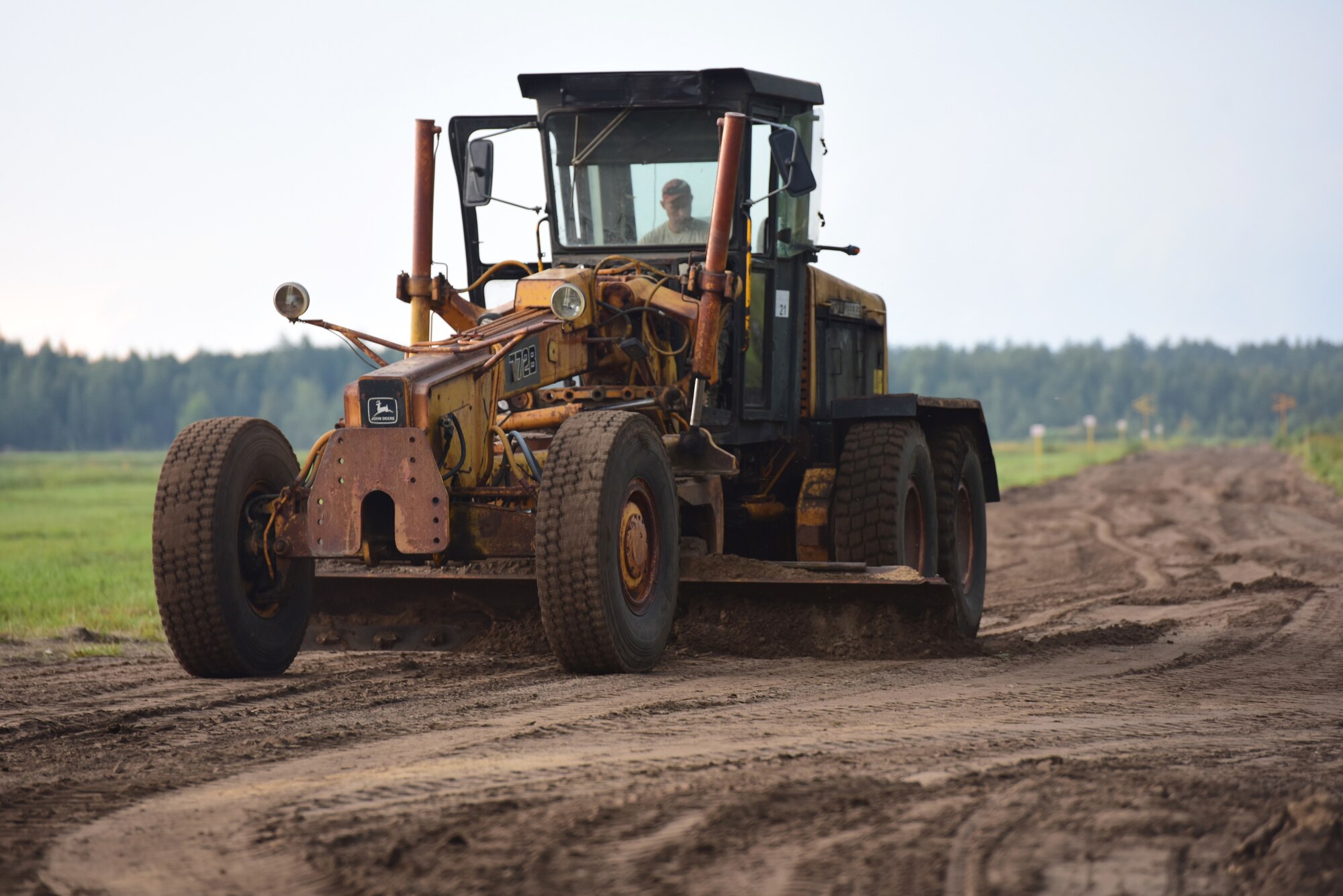 A grader operated by an Airman from the 201st Rapid Engineer Deployable Heavy Operational Repair Squadron Engineers, levels the equipment haul route of the training air-to-ground range being constructed at Brigadier General Kazio Veverskis Training Grounds, Kazlu Ruda, Lithuania, Aug. 14, 2018. The range will include a mock village, bomb circle, simulated runway, fire break, strafe pit and observation point to be used by Lithuanian and other NATO forces. (U.S. Air National Guard photo by Tech. Sgt. Claire Behney/Released)