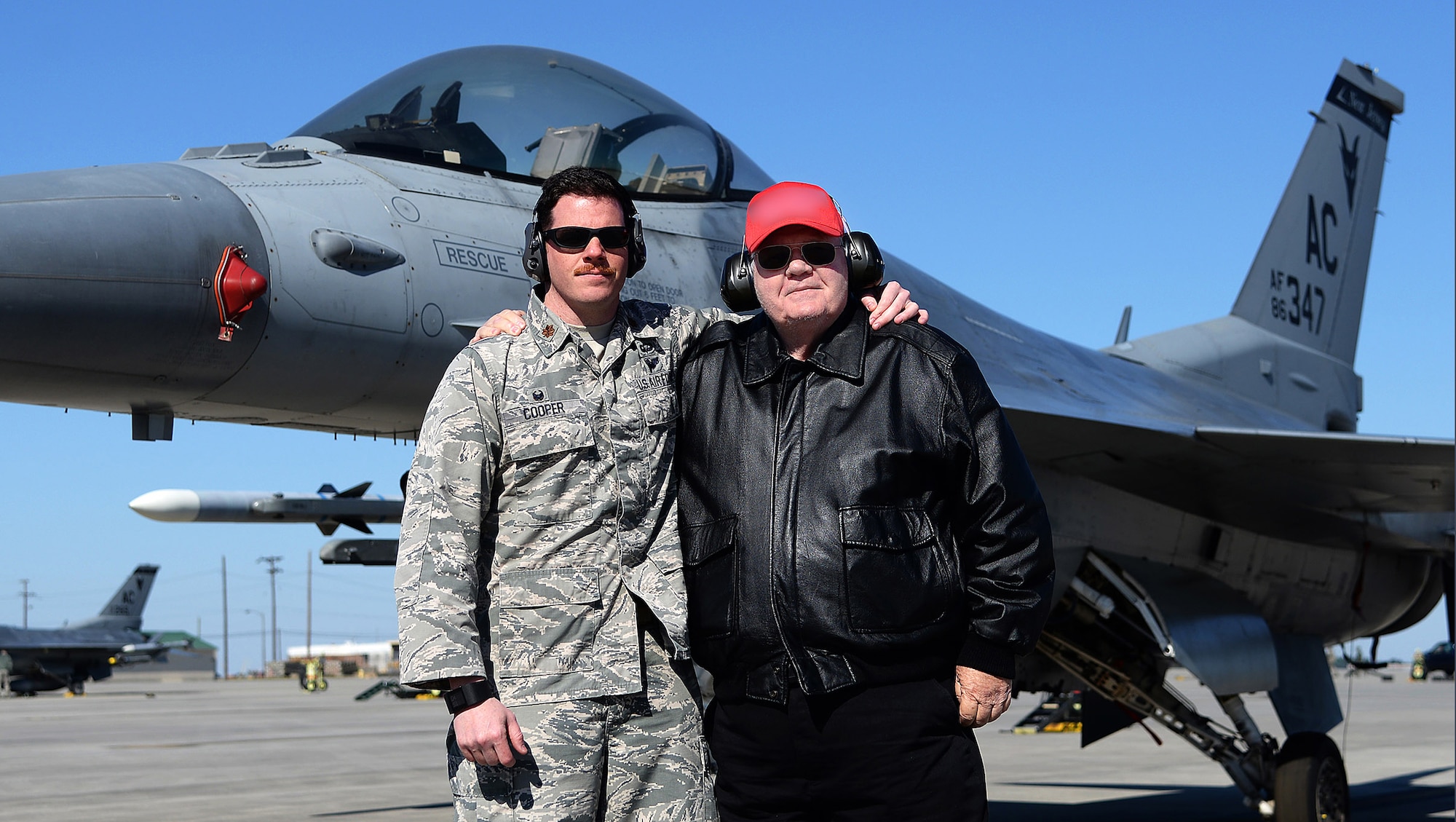 A picture of Maj. Brian T. Cooper, commander of the 177th Fighter Wing Aircraft Maintenance Squadron, New Jersey Air National Guard, and Thomas J. Cooper, a retired Air Force captain, posing for a photo in front of a U.S. Air Force F-16C Fighting Falcon.
