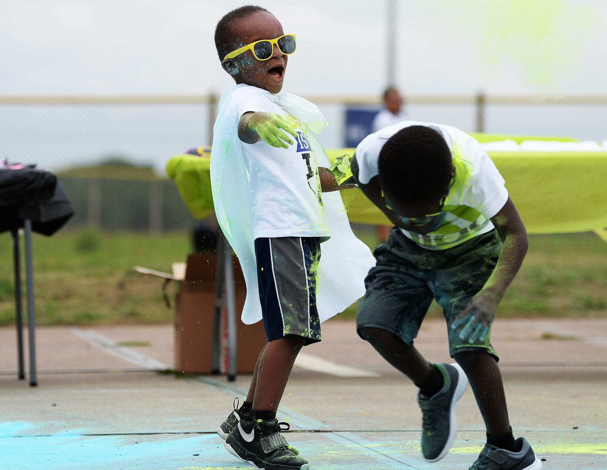 A child throws colored chalk at his brother at a color dash hosted Child and Youth Program, at Royal Air Force Lakenheath, England, Aug. 18, 2018. All proceeds of the color dash will go to the Child and Youth Program advisory board in support of future youth activities. (U.S. Air Force photo/Airman 1st Class Shanice Williams-Jones)
