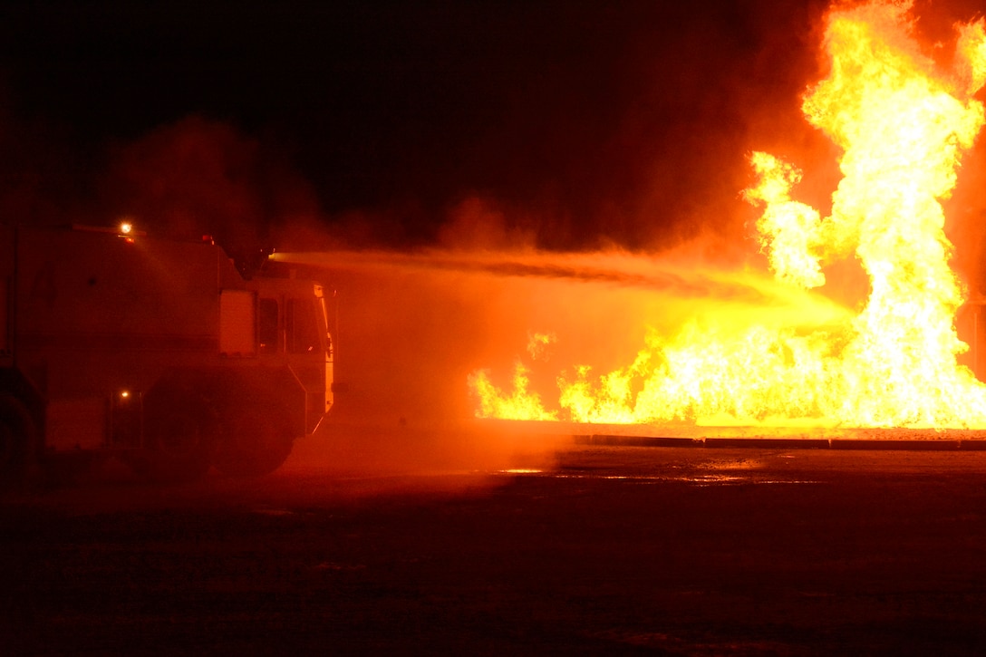 U.S. and coalition troops operate a fire truck hose to combat a simulated fire.