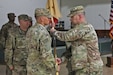 U.S. Army Capt. Filiberto Pacheco (left) and U.S. Army Col. Robert Kuth (right) conduct the exchange of the company colors during the Headquarters Company of Area Support Group Qatar’s change of command at Camp As-Sayliyah, Qatar, July 31, 2018.  The exchange of the company colors symbolized Capt. Pacheco accepting command of the company.