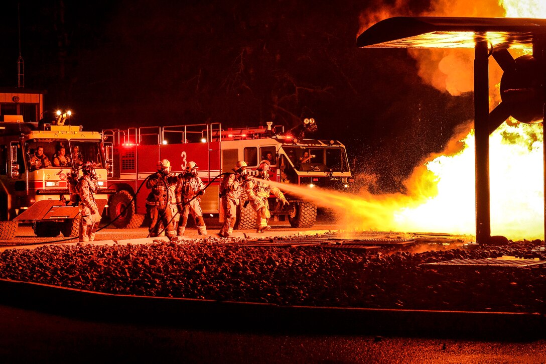 U.S. and coalition troops use fire hoses to combat a simulated aircraft fire.