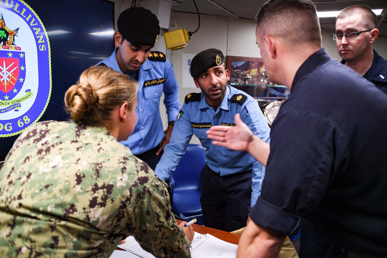 U.S. Navy and Coast Guard sailors discuss an exercise with Kuwaiti sailors.