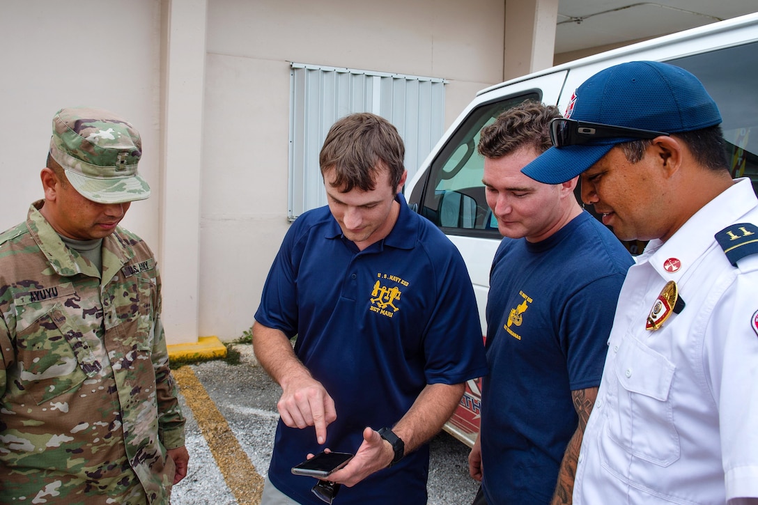 U.S. sailors and civilians exchange information on detonating unexploded ordnance.