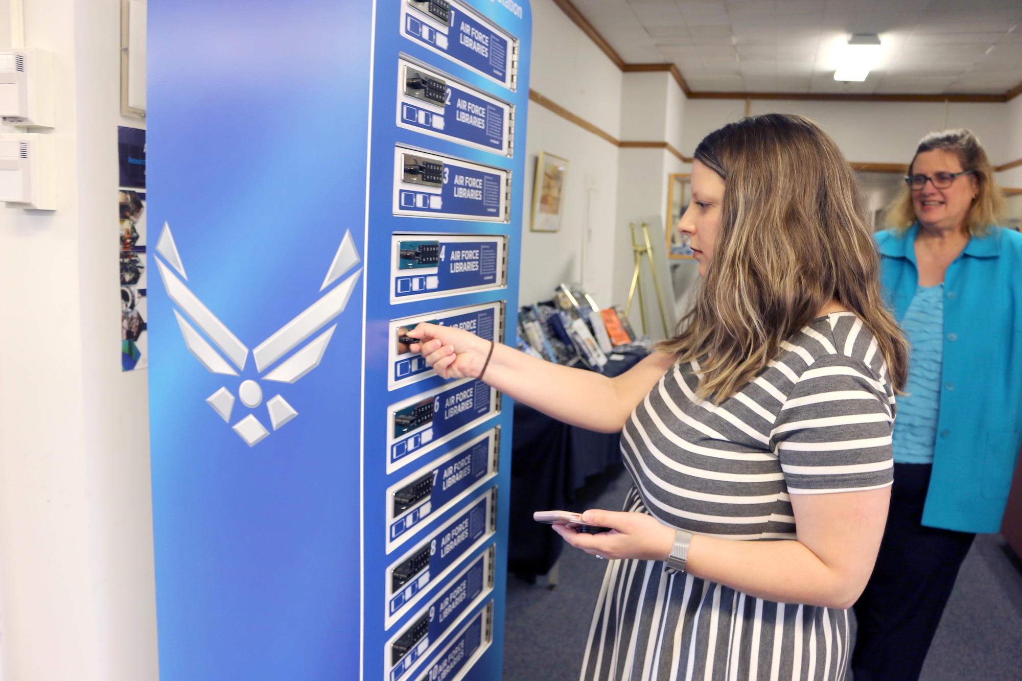 Andrea Hanna follows the instructions provided on the charging station regarding how to lock a stall to secure a device while charging. The charging station was recently made available at the AEDC Technical Library through funding from the Air Force Libraries. The AEDC Technical Library is located in Building 100, at Arnold Air Force Base. (U.S. Air Force photo by Deidre Ortiz)